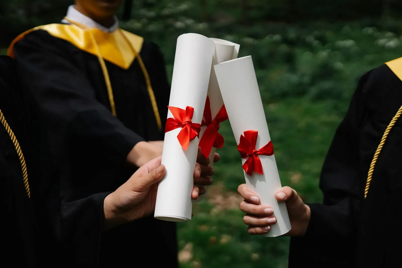 Graduates holding diplomas with red ribbons celebrating at an Irish university ceremony