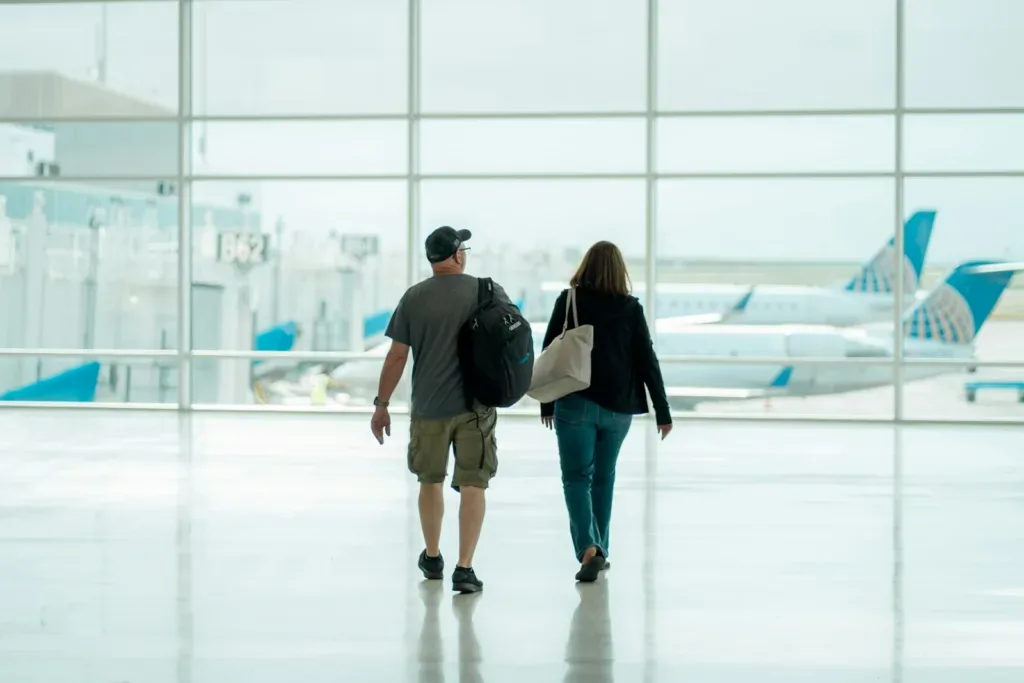 Traveller couple walking through an airport terminal with luggage before their flight