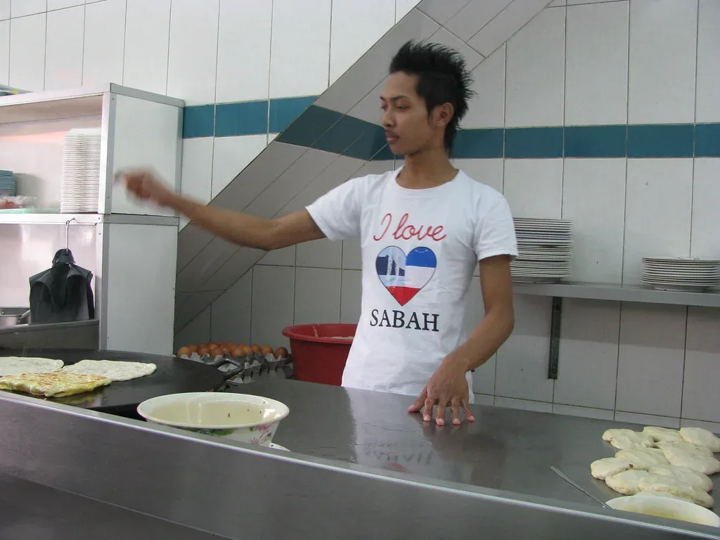 Hands cooking flaky parathas on a pan, a comfort food many Indian students learn to make abroad